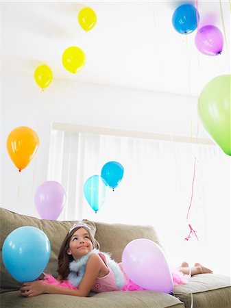 simsearch:693-03305634,k - Young girl (7-9) lying on sofa looking at balloons Stock Photo - Premium Royalty-Free, Code: 693-03305633