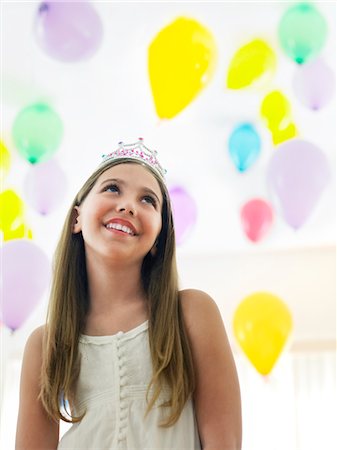 simsearch:693-03305634,k - Girl (10-12) in tiara, smiling, looking up at balloons Stock Photo - Premium Royalty-Free, Code: 693-03305645