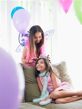 simsearch:693-03305634,k - Two girls (7-9, 10-12) on sofa in party costumes, one adjusting other's tiara Stock Photo - Premium Royalty-Free, Code: 693-03305641