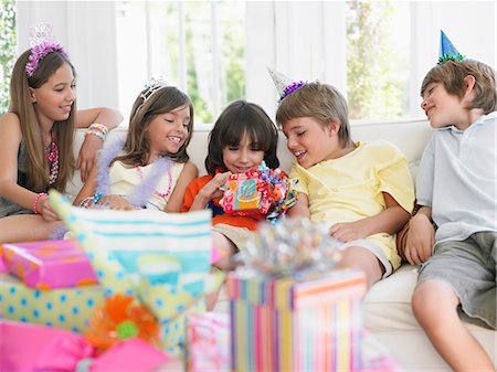 simsearch:693-03305634,k - Children (7-12) sitting on sofa, watching one open birthday present Stock Photo - Premium Royalty-Free, Code: 693-03305656