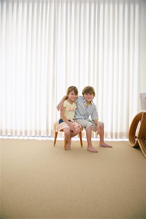 Boy (7-9) and girl (5-6) sitting on stool in room Stock Photo - Premium Royalty-Free, Code: 693-03305758