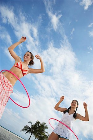 Teenage girls (16-17) playing with hoola hoop on beach, low angle view Stock Photo - Premium Royalty-Free, Code: 693-03305806