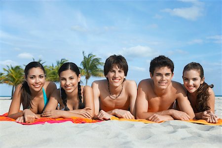Group of teenagers (16-17) lying in row on beach towels, portrait Stock Photo - Premium Royalty-Free, Code: 693-03305814