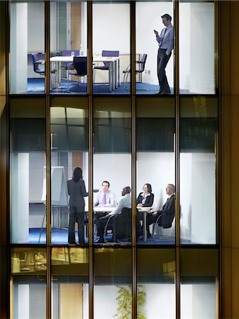 Business man text messaging on floor above group of business people at office meeting, view from building exterior Stock Photo - Premium Royalty-Free, Code: 693-03305993