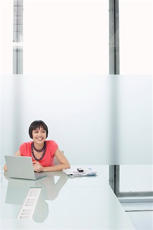 Woman using laptop in modern cubicle Stock Photo - Premium Royalty-Free, Code: 693-03307885