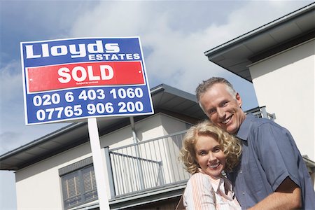 simsearch:693-03308239,k - Couple embracing outside new home with sold sign, portrait Stock Photo - Premium Royalty-Free, Code: 693-03308238