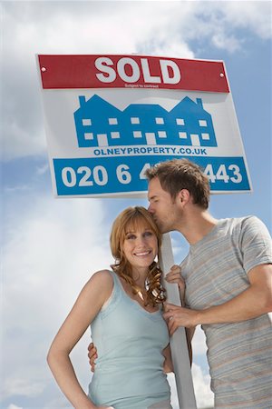 simsearch:693-03308239,k - Couple holding sold sign against sky, man kissing woman Stock Photo - Premium Royalty-Free, Code: 693-03308291