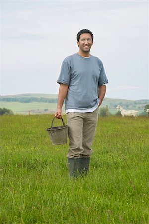 farmer in rubber boots - Man holding bucket in field, portrait Stock Photo - Premium Royalty-Free, Code: 693-03308440