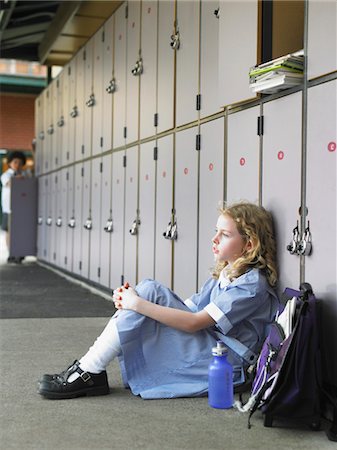 sad girls - Elementary schoolgirl sitting on floor against school lockers Stock Photo - Premium Royalty-Free, Code: 693-03300827