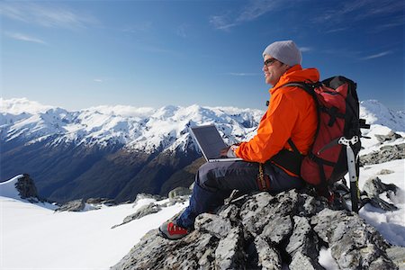 Mountain climber using laptop on mountain peak Stock Photo - Premium Royalty-Free, Code: 693-03300991