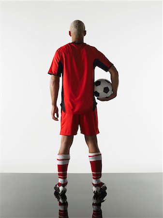 Football player standing holding ball, back view Stock Photo - Premium Royalty-Free, Code: 693-03302998