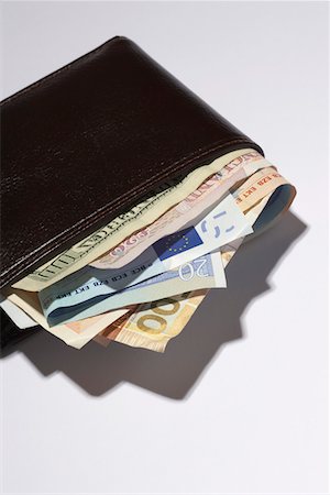 Wallet full of different currencies, in studio Stock Photo - Premium Royalty-Free, Code: 693-03303040