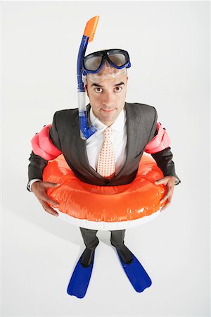 Middle-aged businessman in flippers, inflatable rubber ring, snorkel and goggles Stock Photo - Premium Royalty-Free, Code: 693-03303654