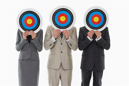 Three business people holding targets in front of faces against white background Stock Photo - Premium Royalty-Free, Code: 693-03303811