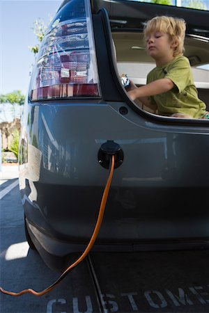 Boy (5-6) sitting in open car trunk at gas station Stock Photo - Premium Royalty-Free, Code: 693-03314209