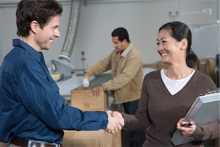 Homme et femme serrant la main dans l'entrepôt de distribution Photographie de stock - Premium Libres de Droits, Code: 693-03315318