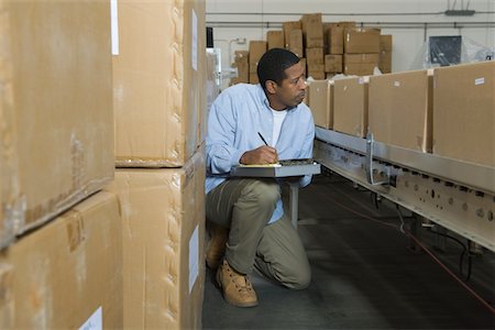 simsearch:693-03315348,k - Man inspecting boxes on conveyor belt in distribution warehouse Foto de stock - Sin royalties Premium, Código: 693-03315372