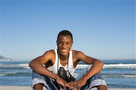 Man sitting on beach with with football boots round his neck Stock Photo - Premium Royalty-Free, Code: 693-03317495