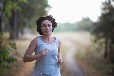 pictures of woman running with short hair - Mid adult woman jogs in woodland Stock Photo - Premium Royalty-Free, Code: 693-03317944