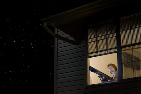 Teenage boy with telescope at open window looking at night sky Stock Photo - Premium Royalty-Free, Code: 693-03317985