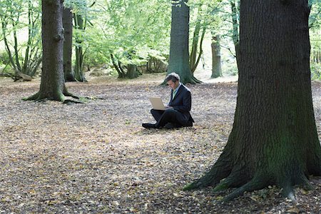 Mid adult business man sitting cross-legged in middle of forest, working on laptop Stock Photo - Premium Royalty-Free, Code: 693-03310029