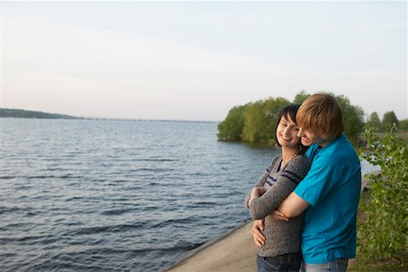 Young Couple Cuddling on Lakeshore Stock Photo - Premium Royalty-Free, Code: 693-03313297