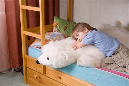 5 year old boy lies on bunk bed with polar bear soft toy Stock Photo - Premium Royalty-Free, Code: 693-03474501