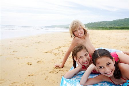 Children reclining, hand on cheek on beach towel on sandy Beach Stock Photo - Premium Royalty-Free, Code: 693-03557034