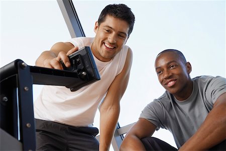 Man showing another man how to use control panel of exercise machine Stock Photo - Premium Royalty-Free, Code: 693-03557206