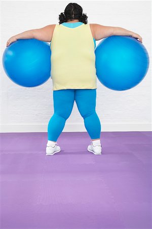 Overweight Woman Holding two Exercise Balls, back view Stock Photo - Premium Royalty-Free, Code: 693-03557455