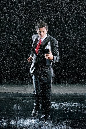 puddle in the rain - Businessman holding binder, running in Rain Stock Photo - Premium Royalty-Free, Code: 693-03565494