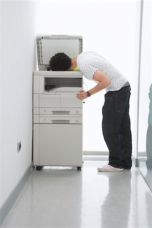 prank - Man putting his head in copy machine in hallway Stock Photo - Premium Royalty-Free, Code: 693-03565782