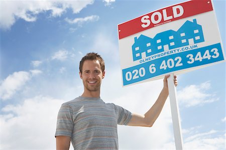 simsearch:693-03308239,k - Man holding sold sign, against sky Stock Photo - Premium Royalty-Free, Code: 693-03565822