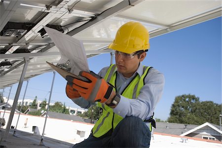 simsearch:693-03643971,k - Maintenance worker refers to notes under solar panel in Los Angeles, California Stock Photo - Premium Royalty-Free, Code: 693-03643961