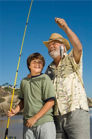 Boy and grandfather showing off fish on beach Stock Photo - Premium Royalty-Free, Code: 693-03686436
