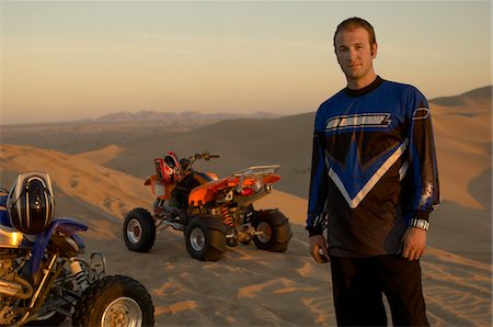 Man standing by quad bikes in desert at sunset Stock Photo - Premium Royalty-Free, Code: 693-03686486