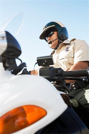 Police officer sitting on motorcycle, low angle view, (low angle view) Stock Photo - Premium Royalty-Free, Code: 693-03686511