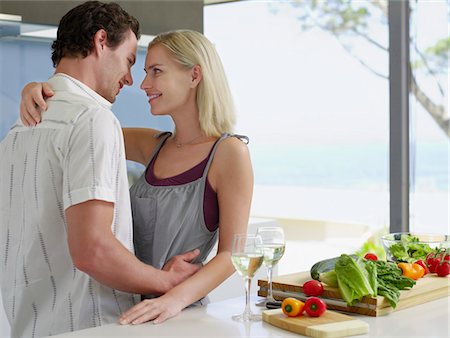 simsearch:693-03304937,k - Young couple hugging in kitchen near countertop with fresh produce and wineglasses Stock Photo - Premium Royalty-Free, Code: 693-03686803