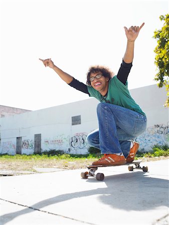 simsearch:693-03363602,k - Young man with arms raised on skateboard, outdoors, portrait Stock Photo - Premium Royalty-Free, Code: 693-03707421