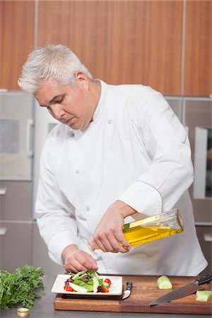 Mid- adult chef pours olive oil over side salad Stock Photo - Premium Royalty-Free, Code: 693-03782520