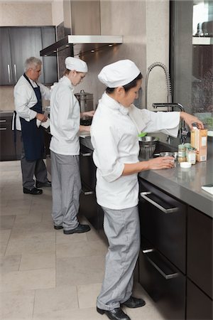 Three chefs work together in busy kitchen Stock Photo - Premium Royalty-Free, Code: 693-03782564
