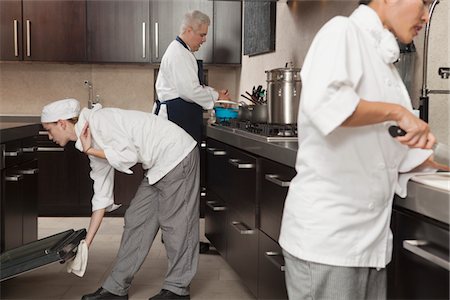 Three chefs work together in busy kitchen Stock Photo - Premium Royalty-Free, Code: 693-03782563