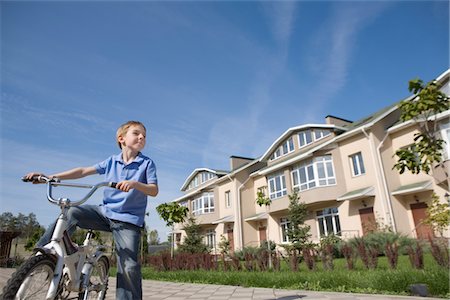 Boy stands with bicycle in new housing development Stock Photo - Premium Royalty-Free, Code: 693-03782627