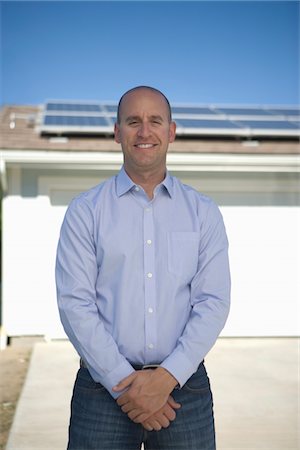 simsearch:693-03643971,k - A man standing infront of part of a house with solar panelling on Stock Photo - Premium Royalty-Free, Code: 693-03782691