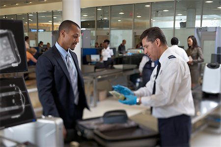 Garde de sécurité examine le contenu de la valise les hommes d'affaires à l'aéroport Photographie de stock - Rights-Managed, Code: 700-05821743