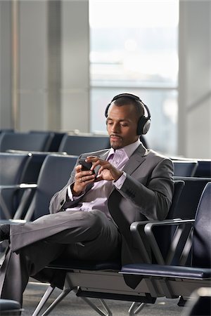 people looking phones - Businessman Wearing Headphones in Waiting Area of Airport Stock Photo - Rights-Managed, Code: 700-05821763