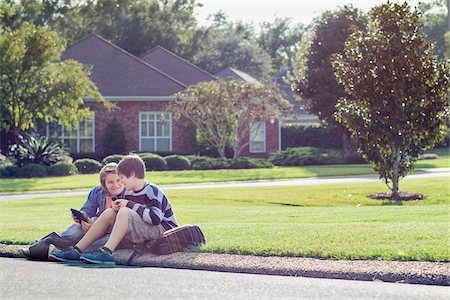 Two Boys Sitting on Neighbourhood Curb with Handheld Electronics Stock Photo - Rights-Managed, Code: 700-06439140