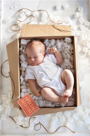 postal - High Angle View of Newborn Baby Girl in a White Onesie in a Shipping Box Labeled as a Special Delivery with Packing Foam and Twine Stock Photo - Rights-Managed, Code: 700-06532016