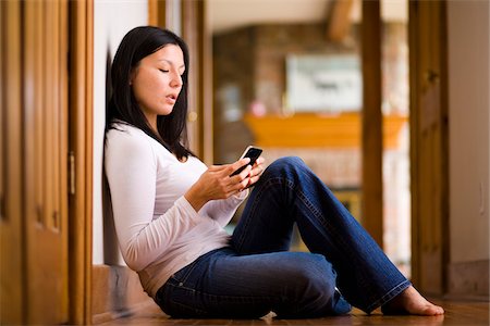 sitting on floor - Woman sitting on the floor and sending a text message on a smart phone Stock Photo - Rights-Managed, Code: 700-06773487