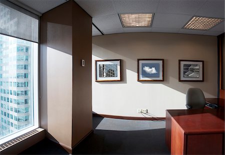 Interior of vacant office with desk, chair, and framed photographs on wall Stock Photo - Rights-Managed, Code: 700-06808931